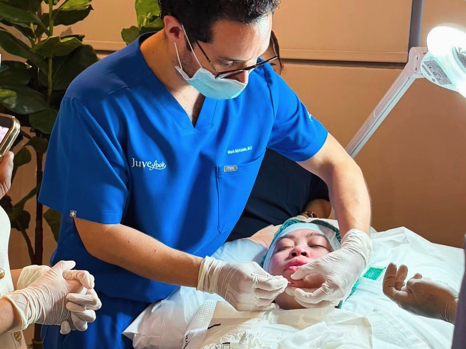 Dr McKelvie, masked and gloved, delivering a mid-face treatment to a reclined patient.